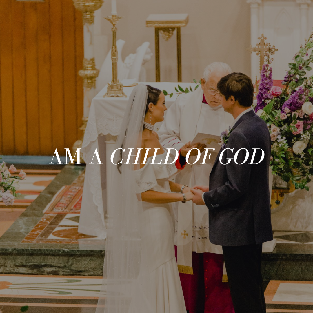 A wedding ceremony with a bride and groom holding hands in front of a priest inside a church, surrounded by floral arrangements.