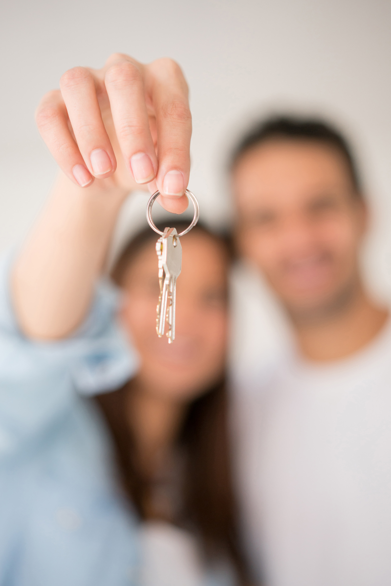 First-time home buyer holding new house keys on the front porch of a Raleigh, North Carolina home