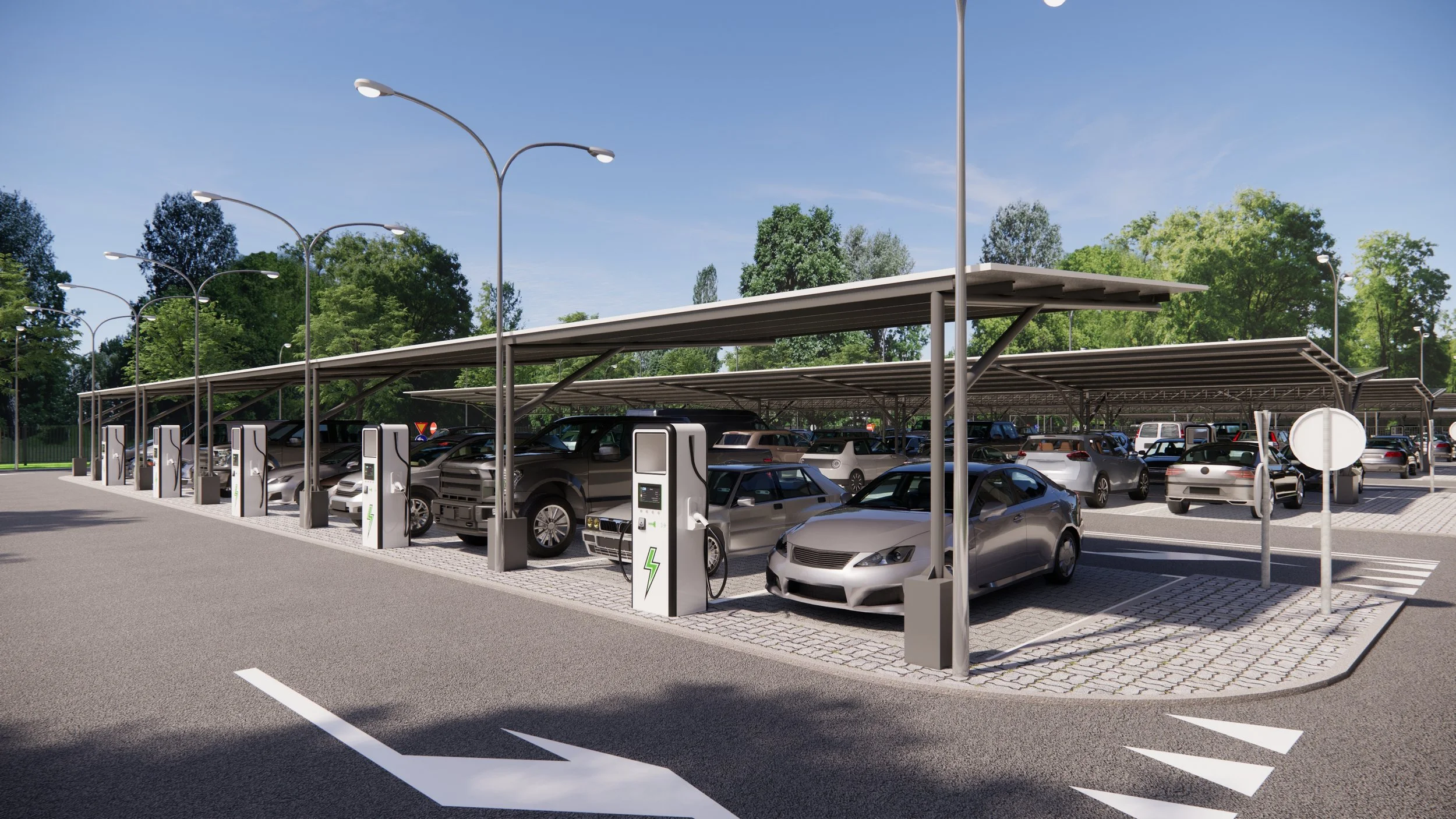 Electric vehicle charging station with multiple cars parked under a covered structure in a parking lot surrounded by greenery.