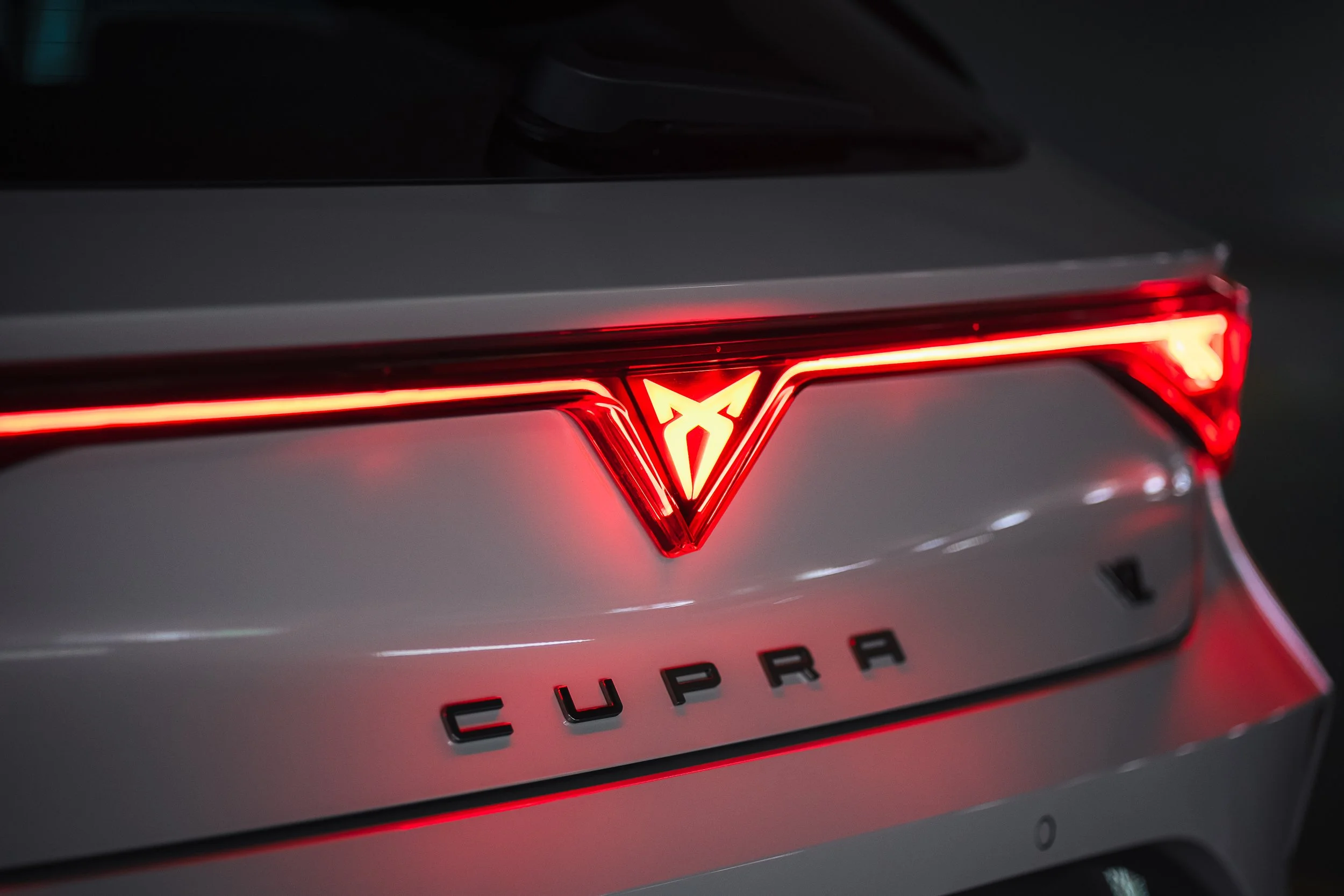 Rückansicht eines Volkswagen-Cupra-Autos mit beleuchteter Marke und Modellbezeichnung.