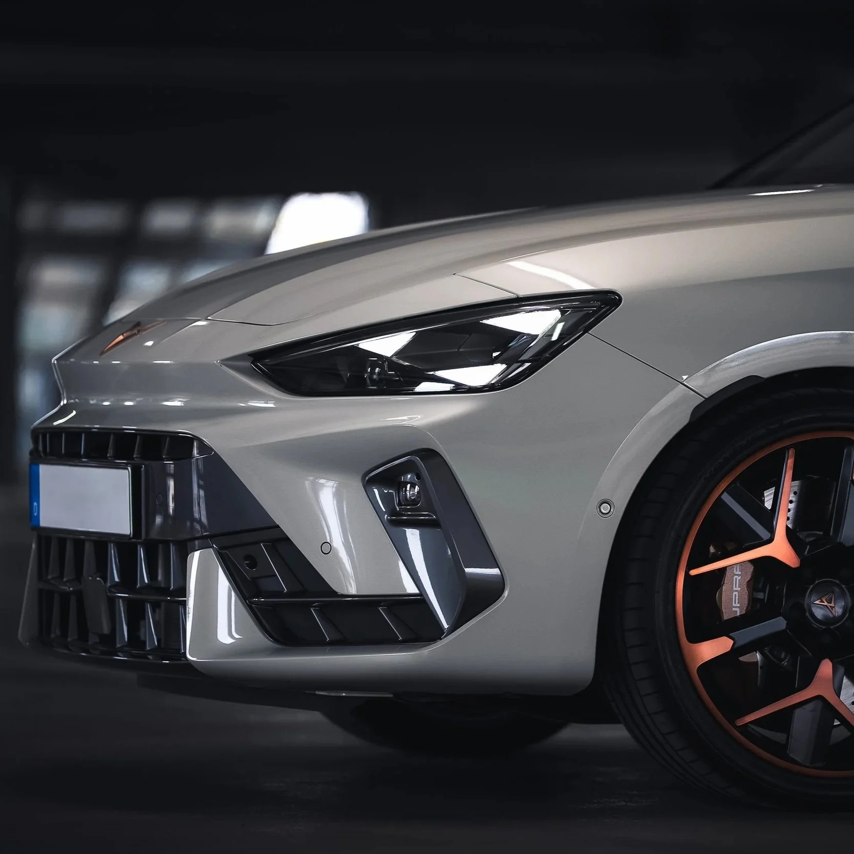 Nahaufnahme des vorderen Teils eines silbernen Sportwagens mit schwarzen Scheinwerfern und roten Akzenten im Rad.