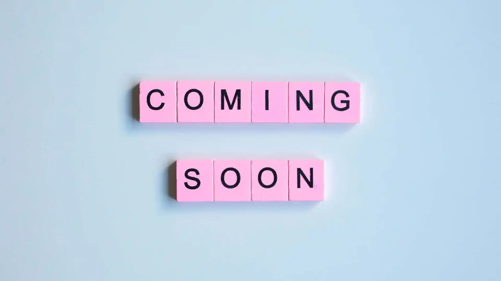 Pink letter tiles spell out 'COMING' above and 'SOON' below on a light blue background.