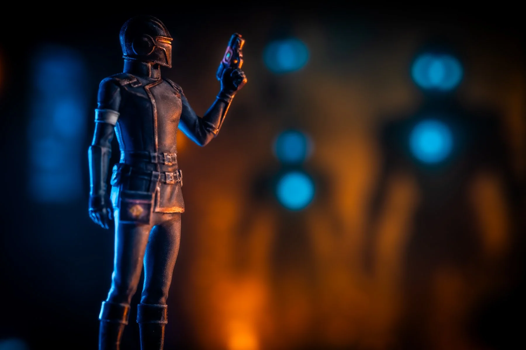 Close-up of a black sci-fi female action figure with a helmet, posed with a gun, against a background of blurred blue and orange lights.