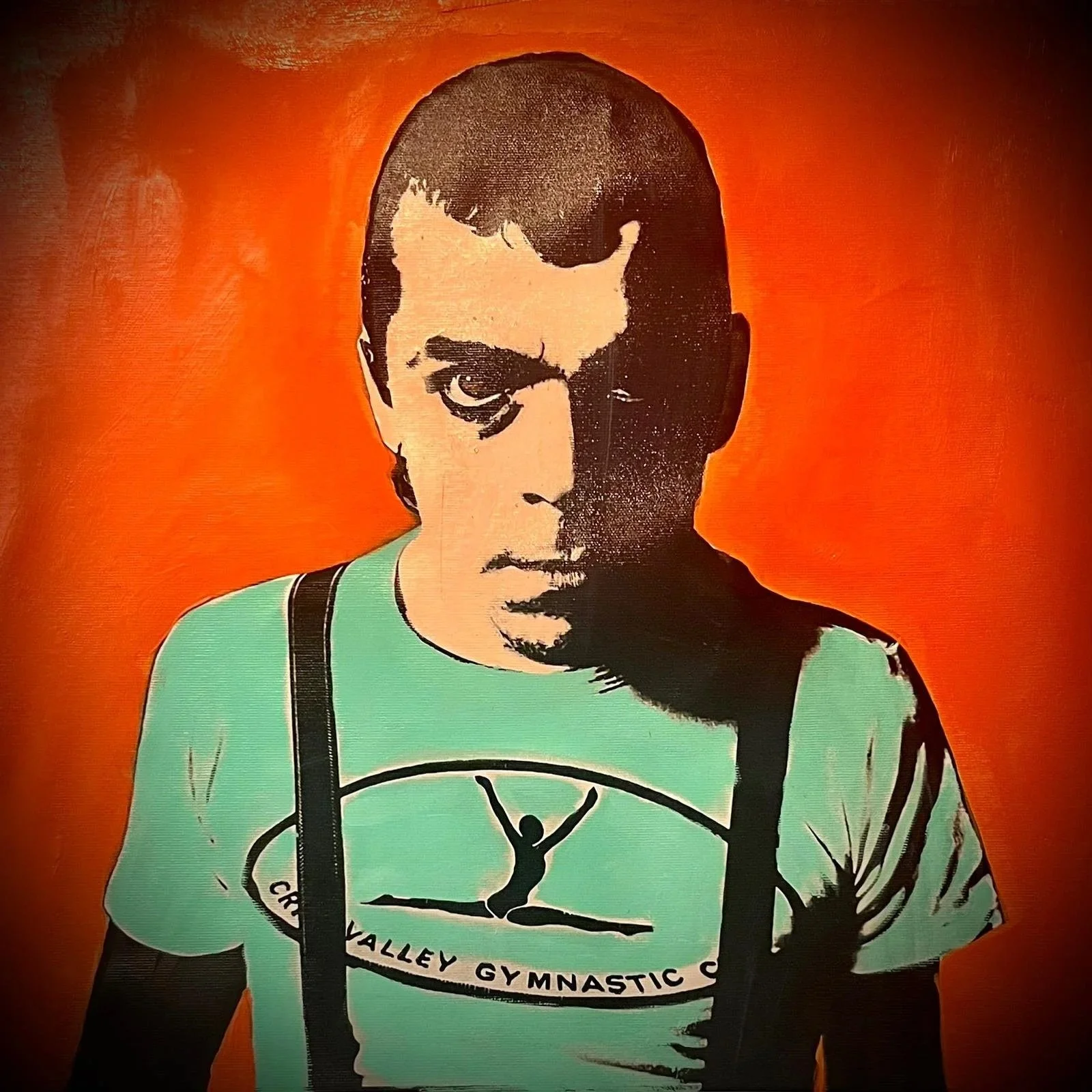 Street art portrait of a young man with short dark hair, wearing a mint green t-shirt with a gymnast logo and black suspenders, against an orange background.