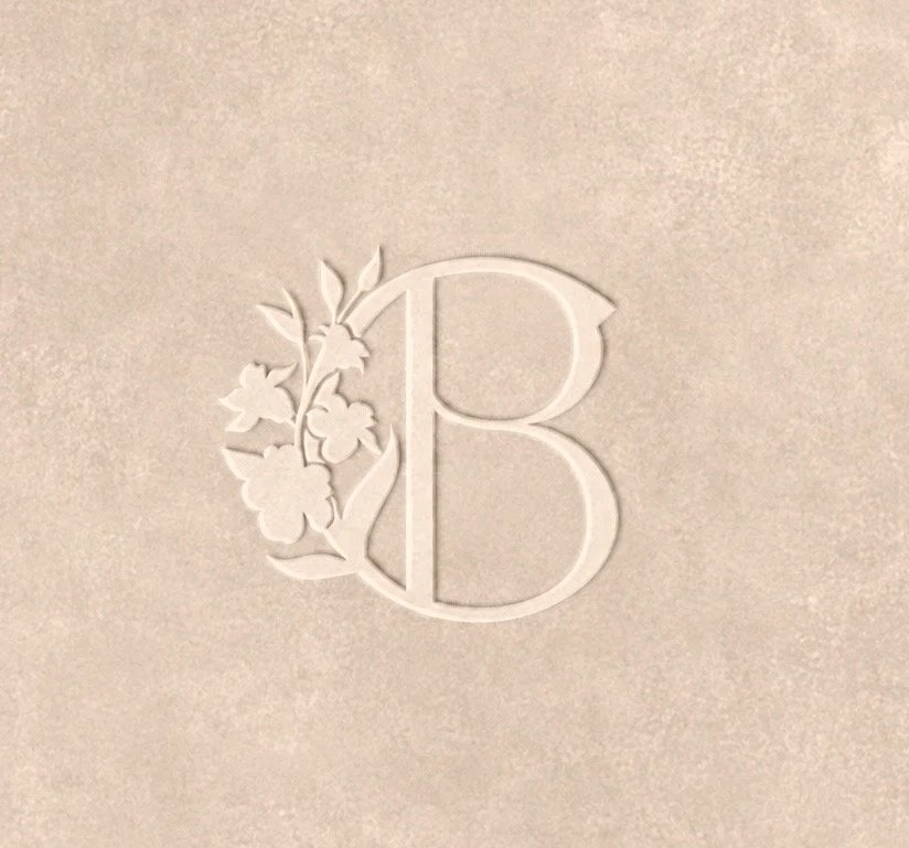 Embossed letter 'B' with a floral design on a light-colored textured surface.