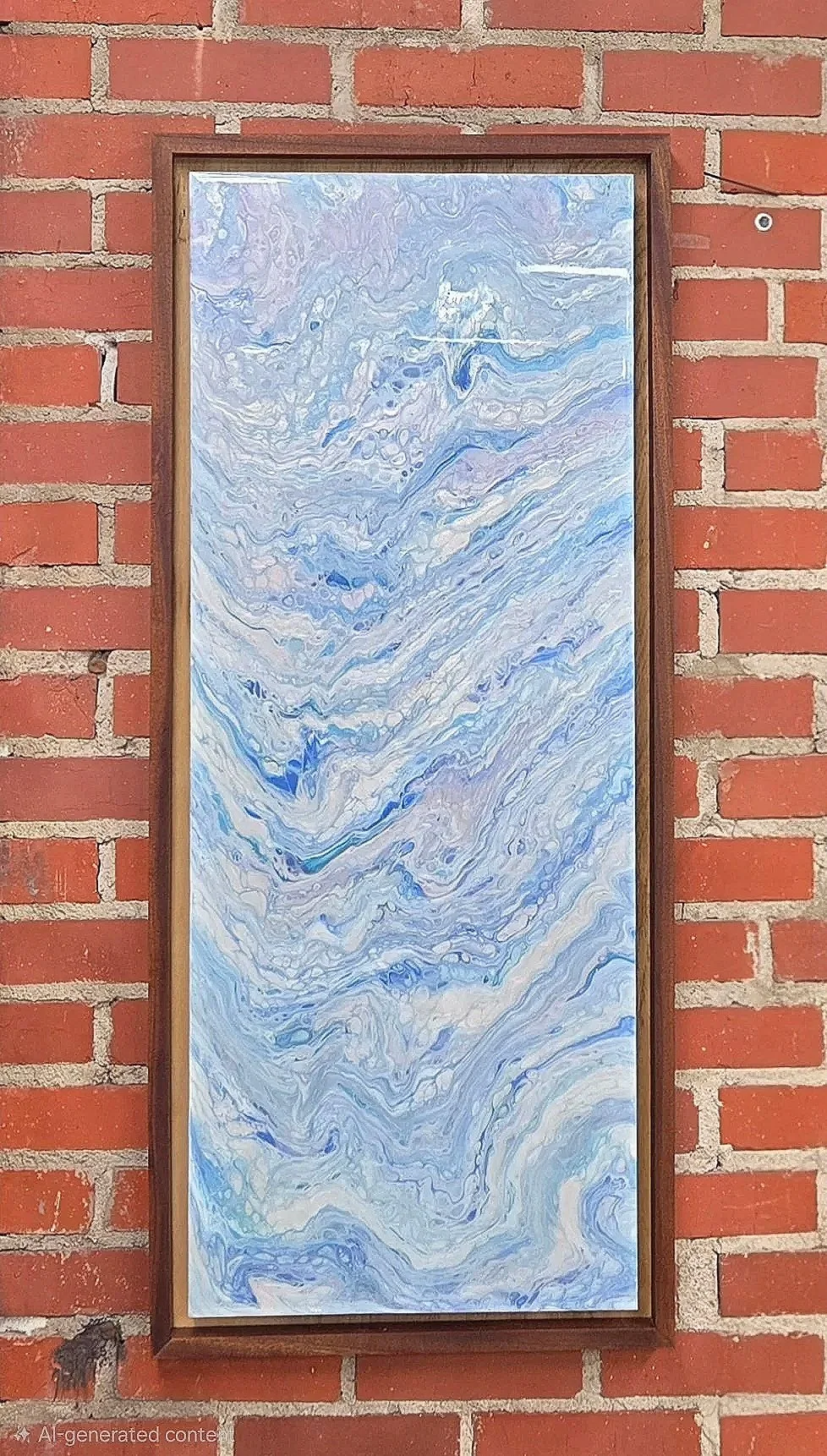 A framed abstract painting with swirling blue, white, and purple patterns, hanging on a red brick wall.