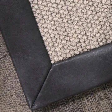 Close-up of a carpet corner on a black sofa with wood flooring.
