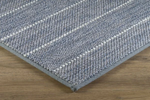 Close-up of a gray striped carpet with a textured pattern on a wooden floor.