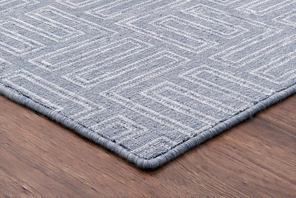 Close-up of a blue geometric patterned area rug on hardwood flooring.