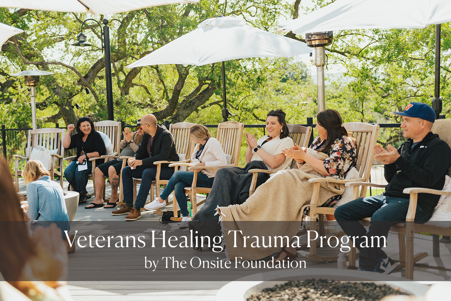 Outdoor porch with wooden rocking chairs and decorative pillows, overlooking a mountainous landscape in the background.