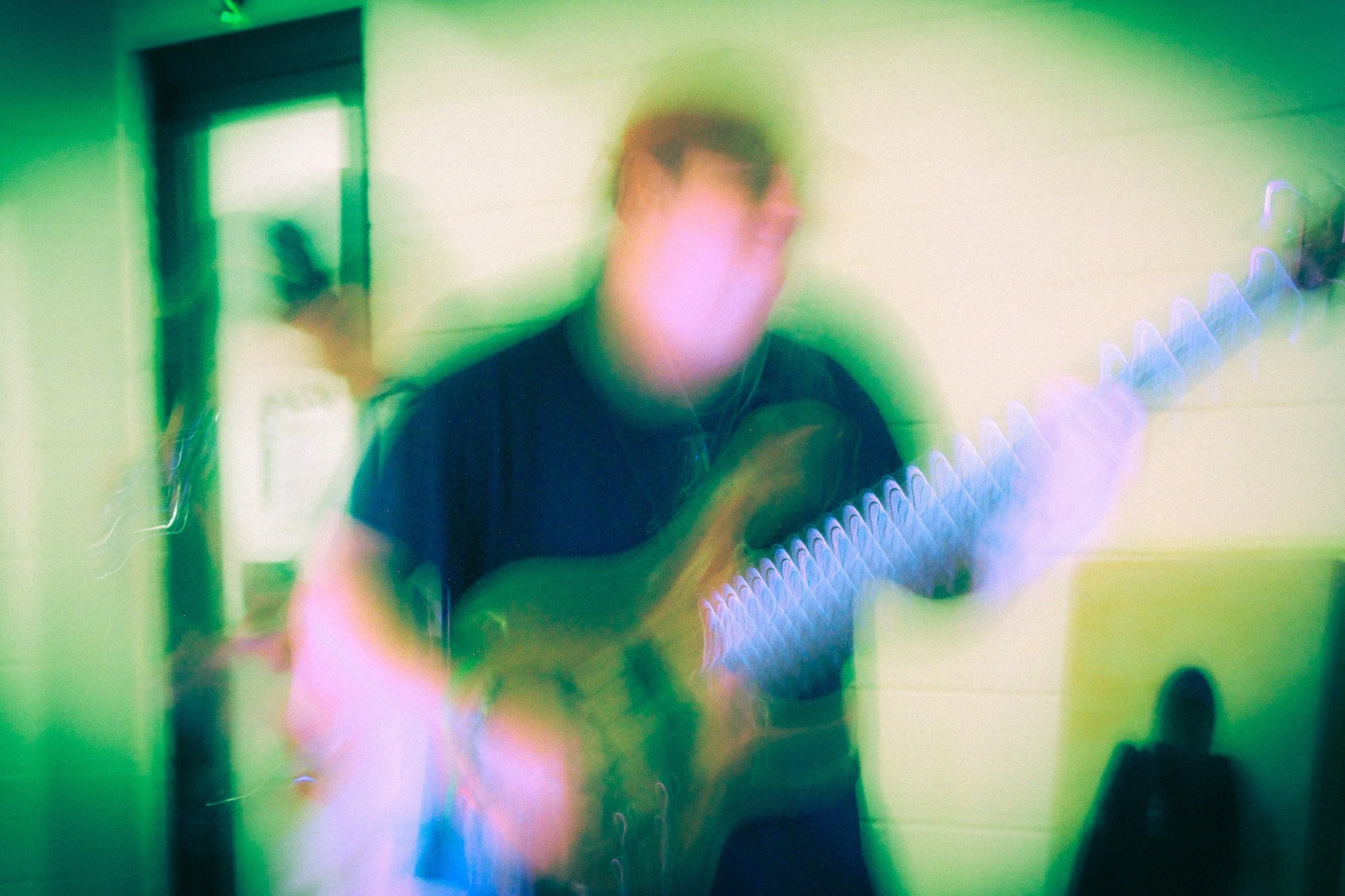 Person playing guitar with colorful light effects in an indoor setting.