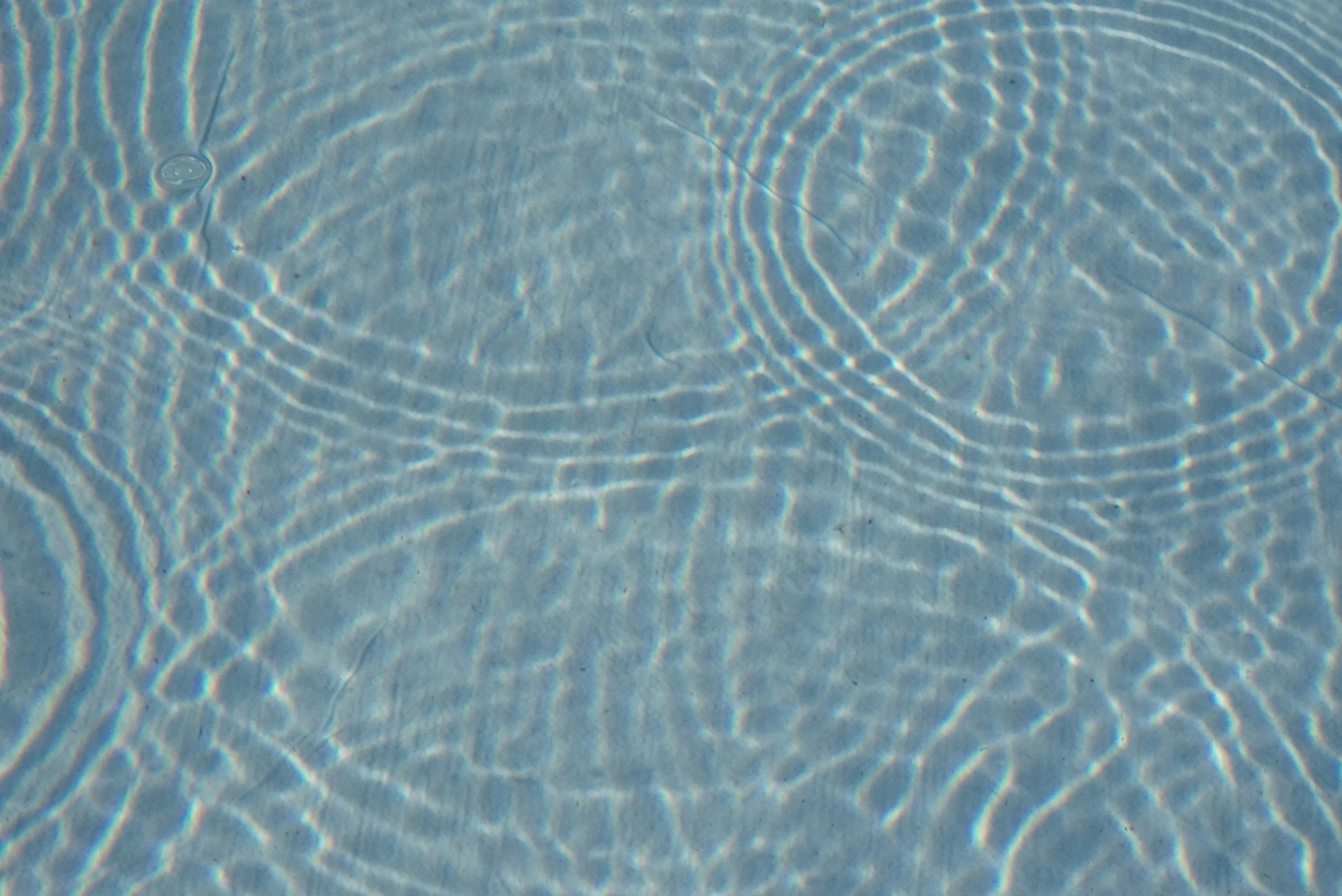 Close-up of water with sunlight reflections creating ripples and patterns.
