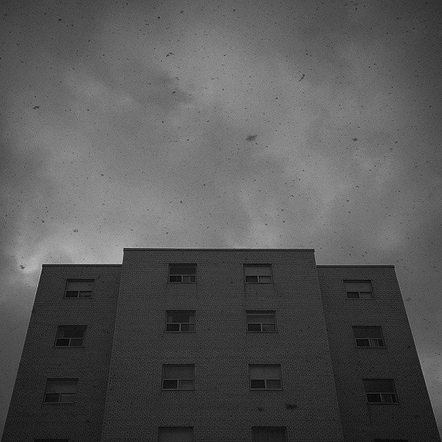 A tall multi-story building with a brick exterior against a cloudy sky.
