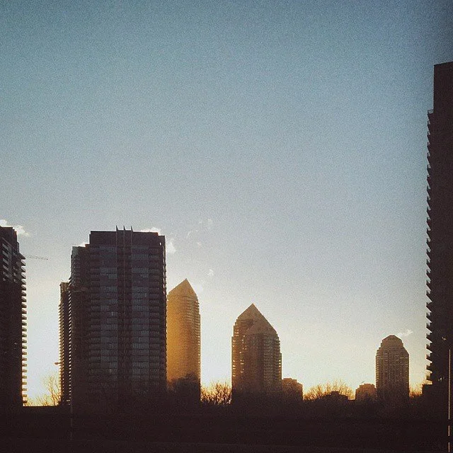 Silhouette of skyscrapers at sunset or sunrise, with the sky transitioning from light to dark.