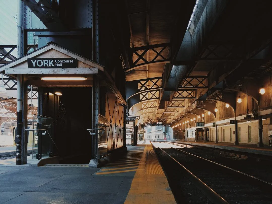 Empty train platform at York Concourse Hall station with an underground passage entrance on the left and train tracks on the right, lit by ceiling lights.