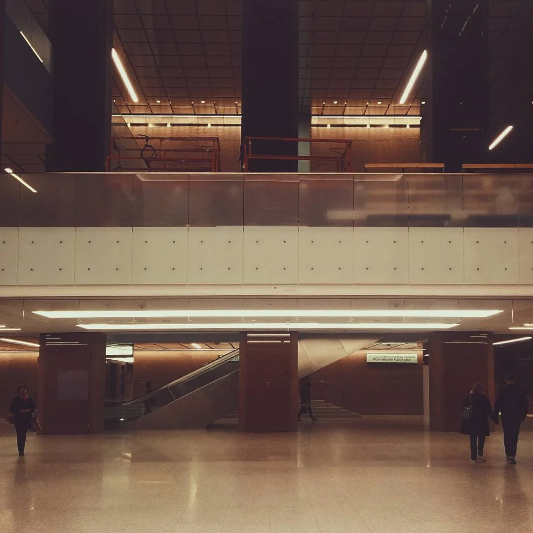 Interior of a modern building with a spacious open area, escalator, and people walking.