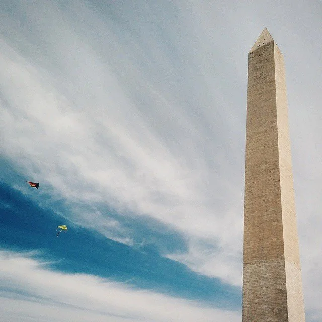The Washington Monument in Washington D.C. with two kites flying in the sky.