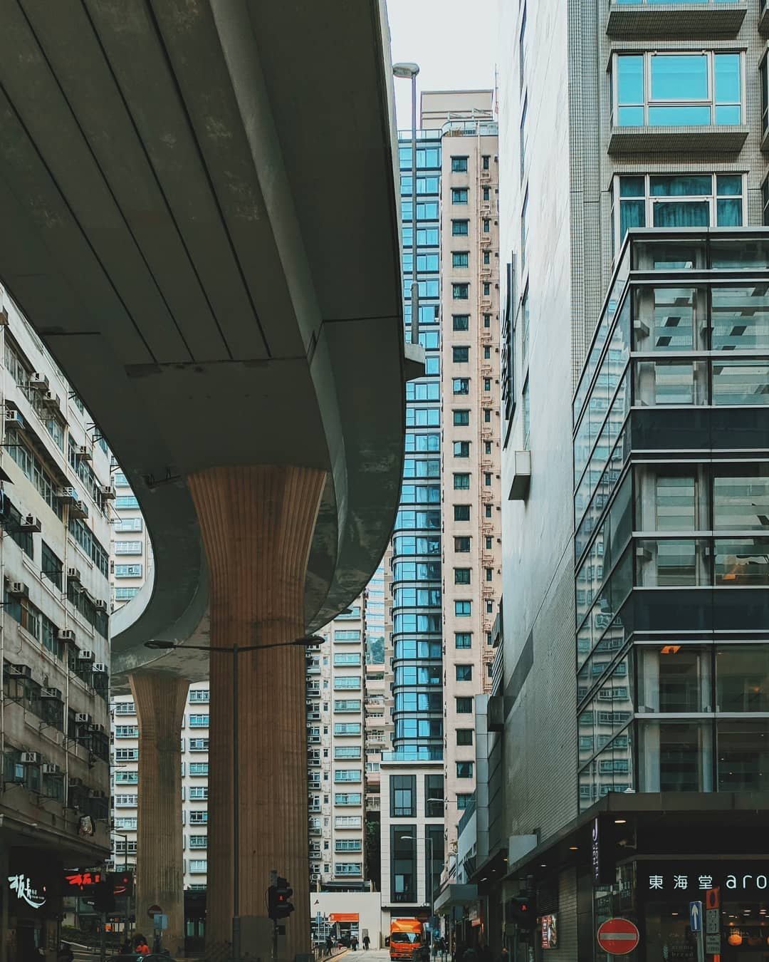 City street scene with high-rise buildings and an elevated highway supported by large wooden columns.