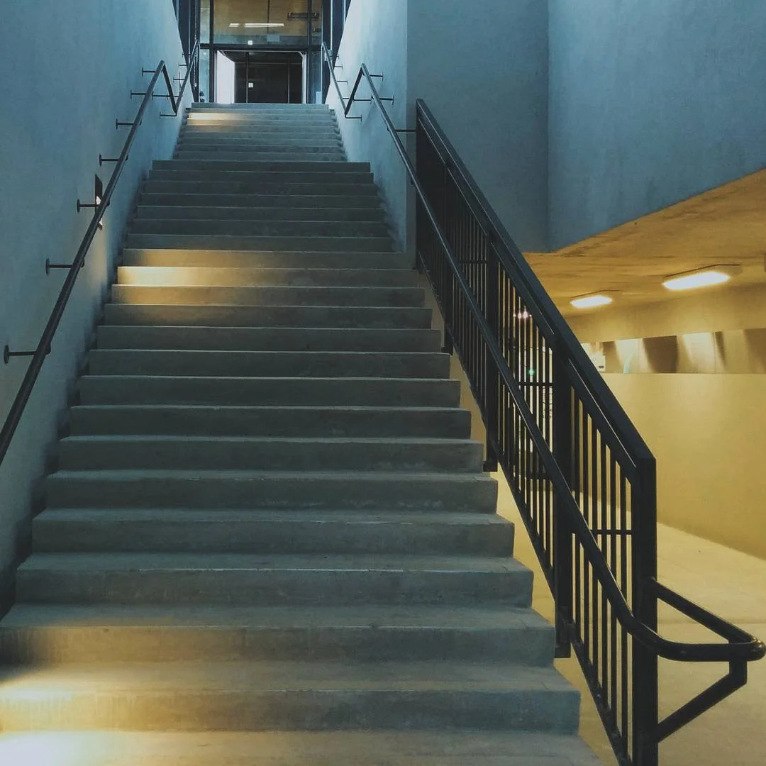 Concrete staircase with handrails on both sides inside a modern building.