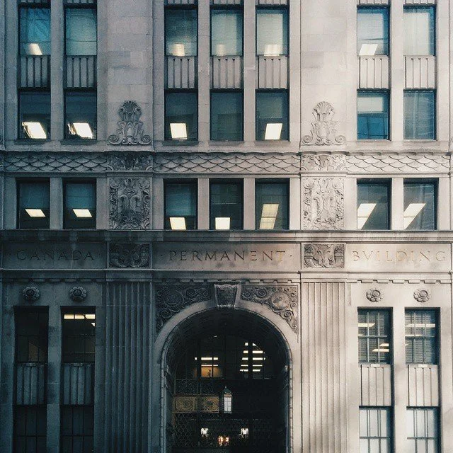 Front view of a historic government building with detailed architectural carvings and the inscription 'Canada Permanent Building' above the entrance.
