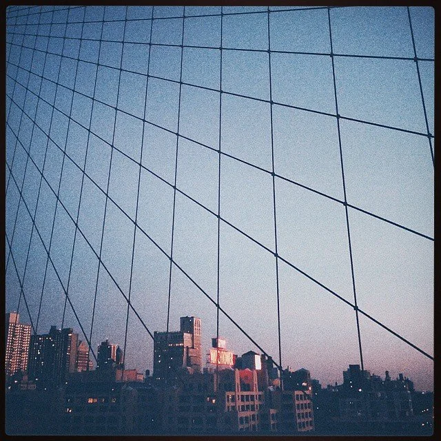 View of a city skyline through a large window with a grid pattern of lines.