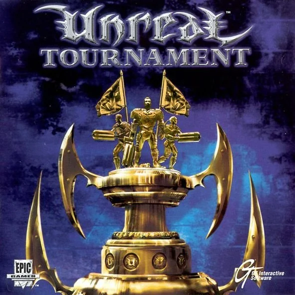 Cover art for Unreal Tournament, showing a golden trophy with three armored figures and flags on top, against a dark blue background with clouds.