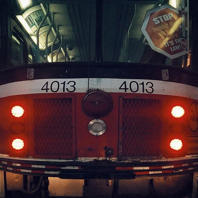 The front of a red bus with route number 4013, showing two red lights on each side and a stop sign in the window that says 'STOP'.