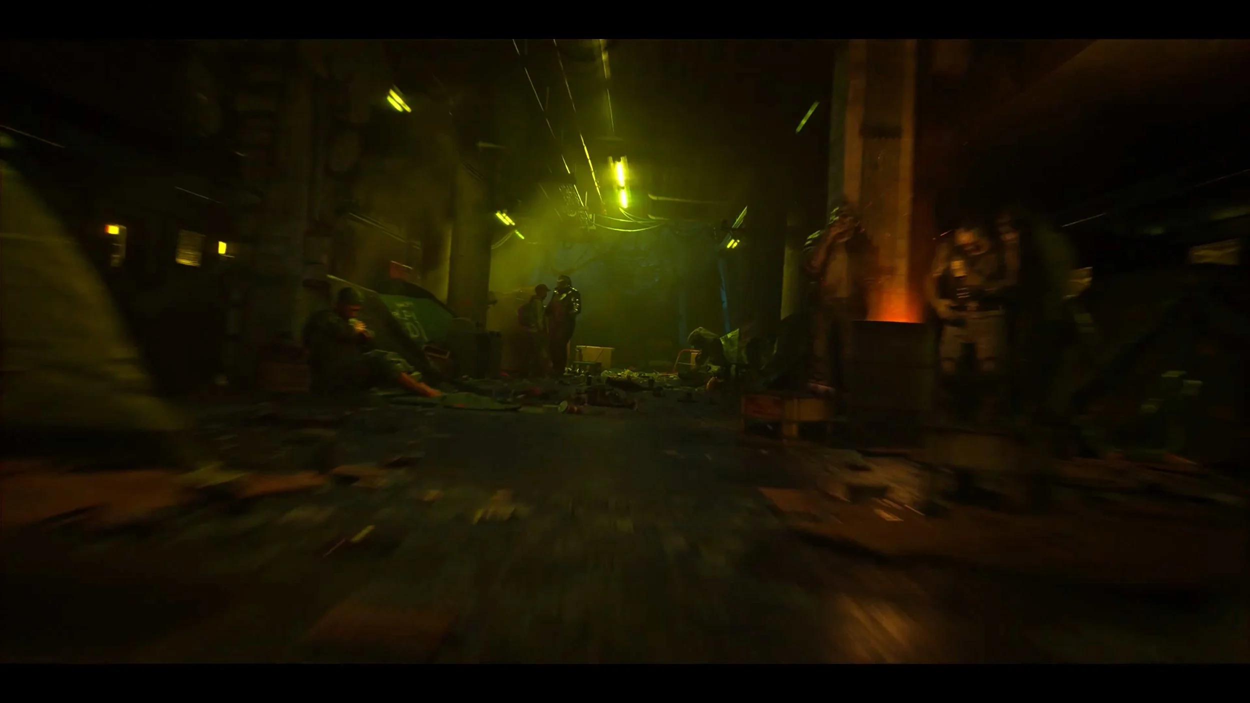 Dark, chaotic scene with people working or fighting, scattered objects, and green and yellow lighting.