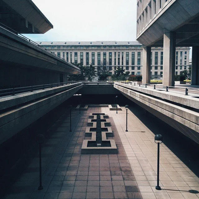 Empty parking lot between modern office buildings with a geometric pattern on the ground.