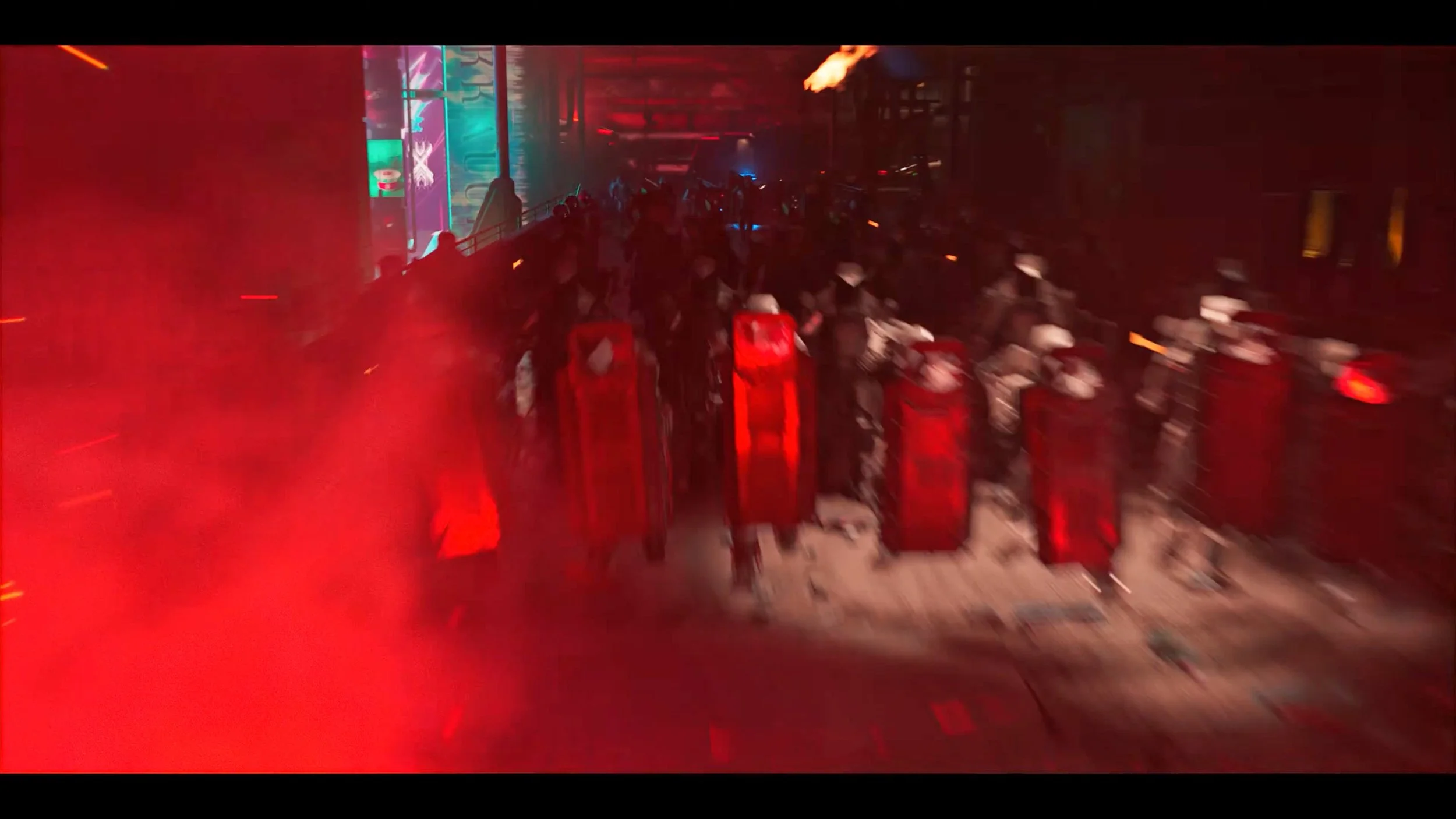 A scene with riot police in black gear and helmets, holding red shields, with red smoke or lights around them in an urban setting at night.