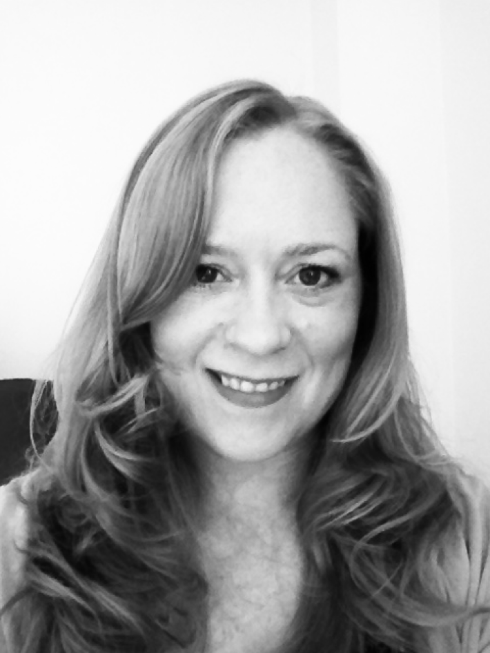 A black and white photo of a woman with long, wavy hair smiling at the camera.
