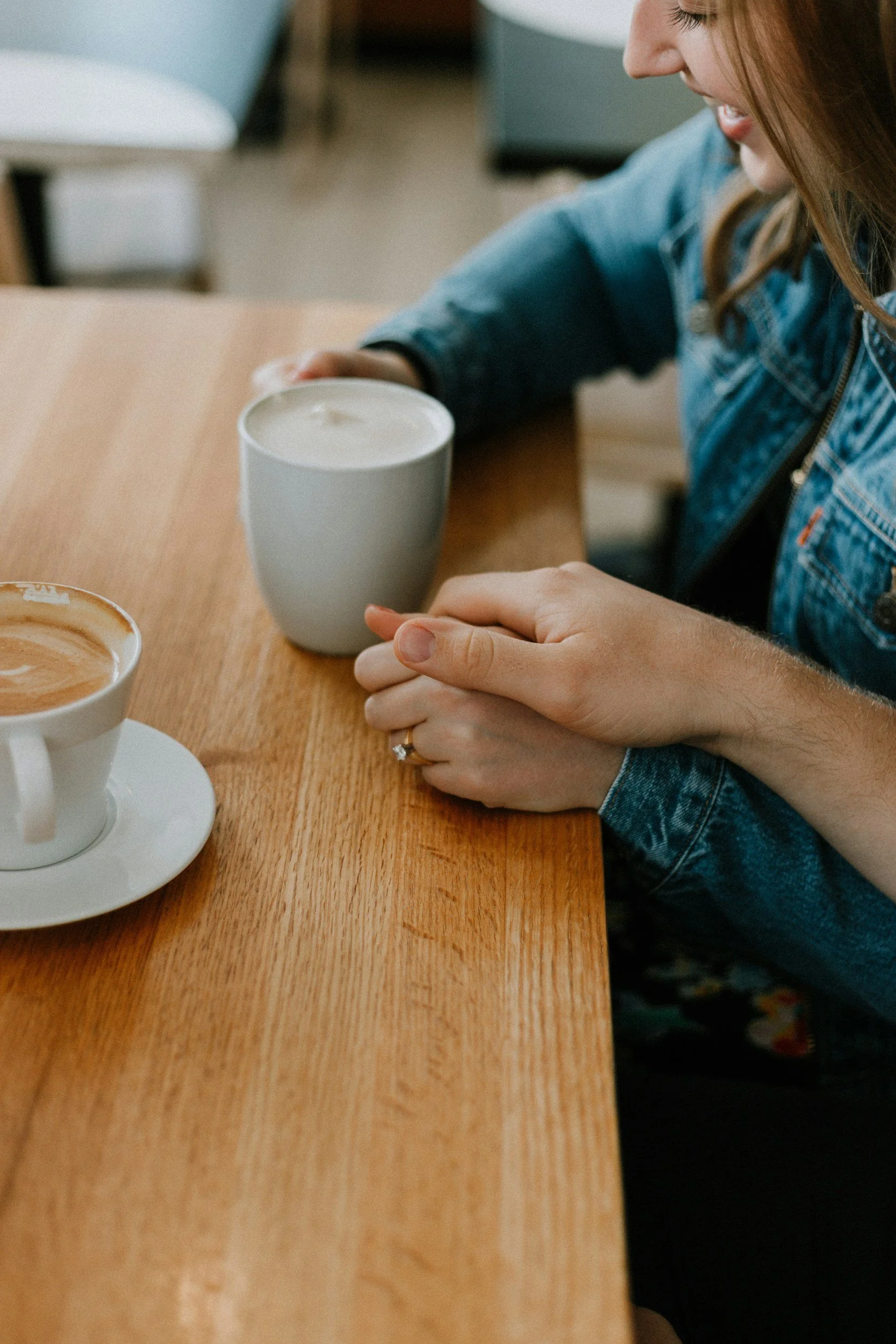 A woman with red hair sitting at a café table with coffee, reflecting on her journey toward healing and self-discovery through anxiety therapy.