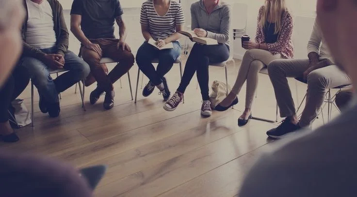 Group of people sitting in a circle during a meeting or discussion.