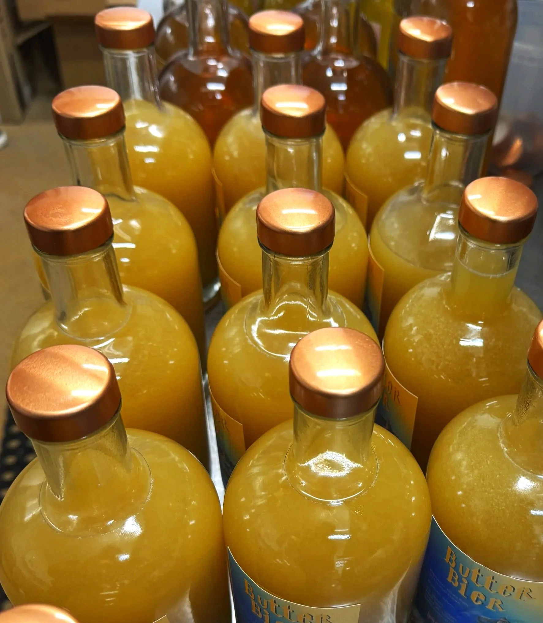 Multiple bottles of butter beer with copper caps on a display shelf.