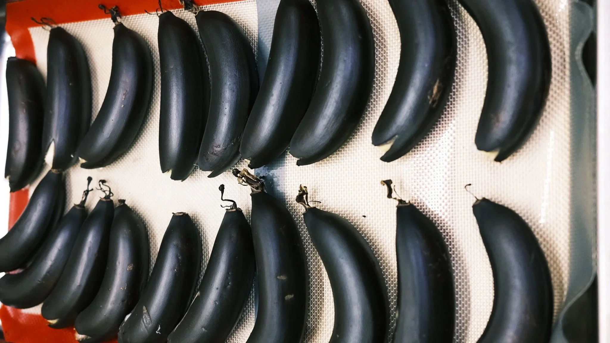 Black bananas arranged on a textured tray.