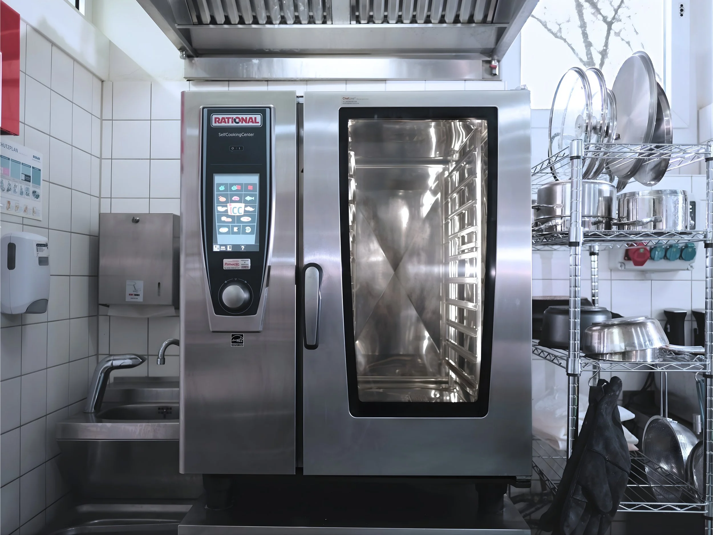 Commercial kitchen sterilizer with stainless steel exterior, digital control panel, glass door, and shelves with pots and pans.