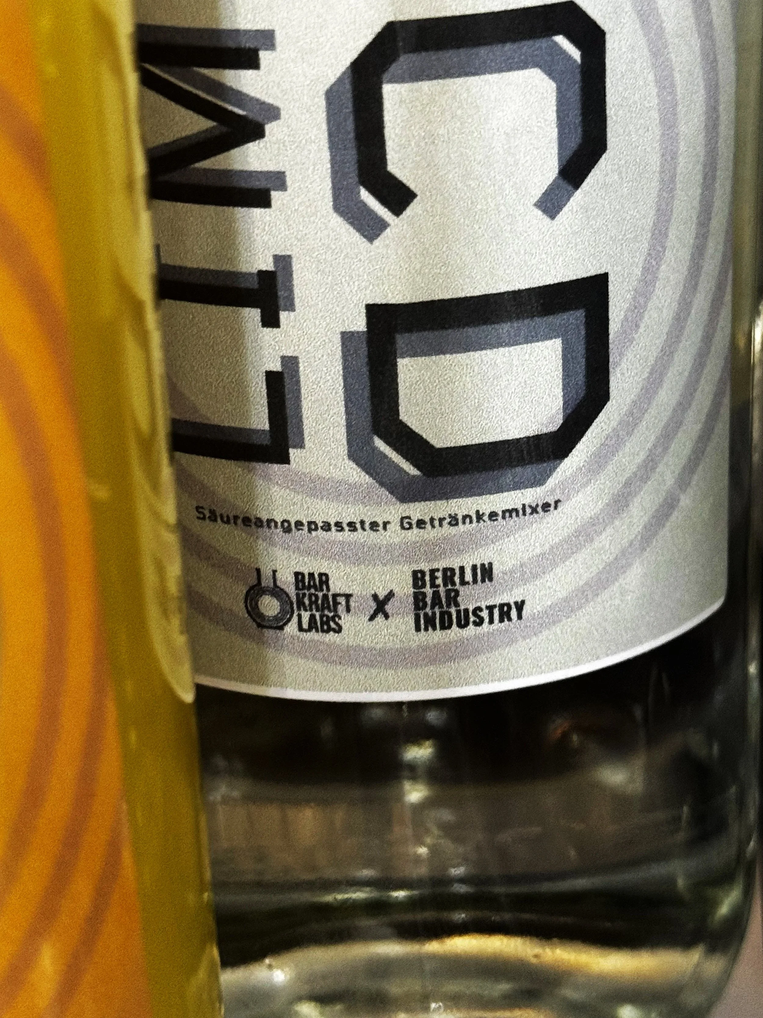 Close-up of a beverage label featuring large, stylized numbers '20' and text indicating a collaboration between Bar Kraft Lab and Berlin Bar Industry.