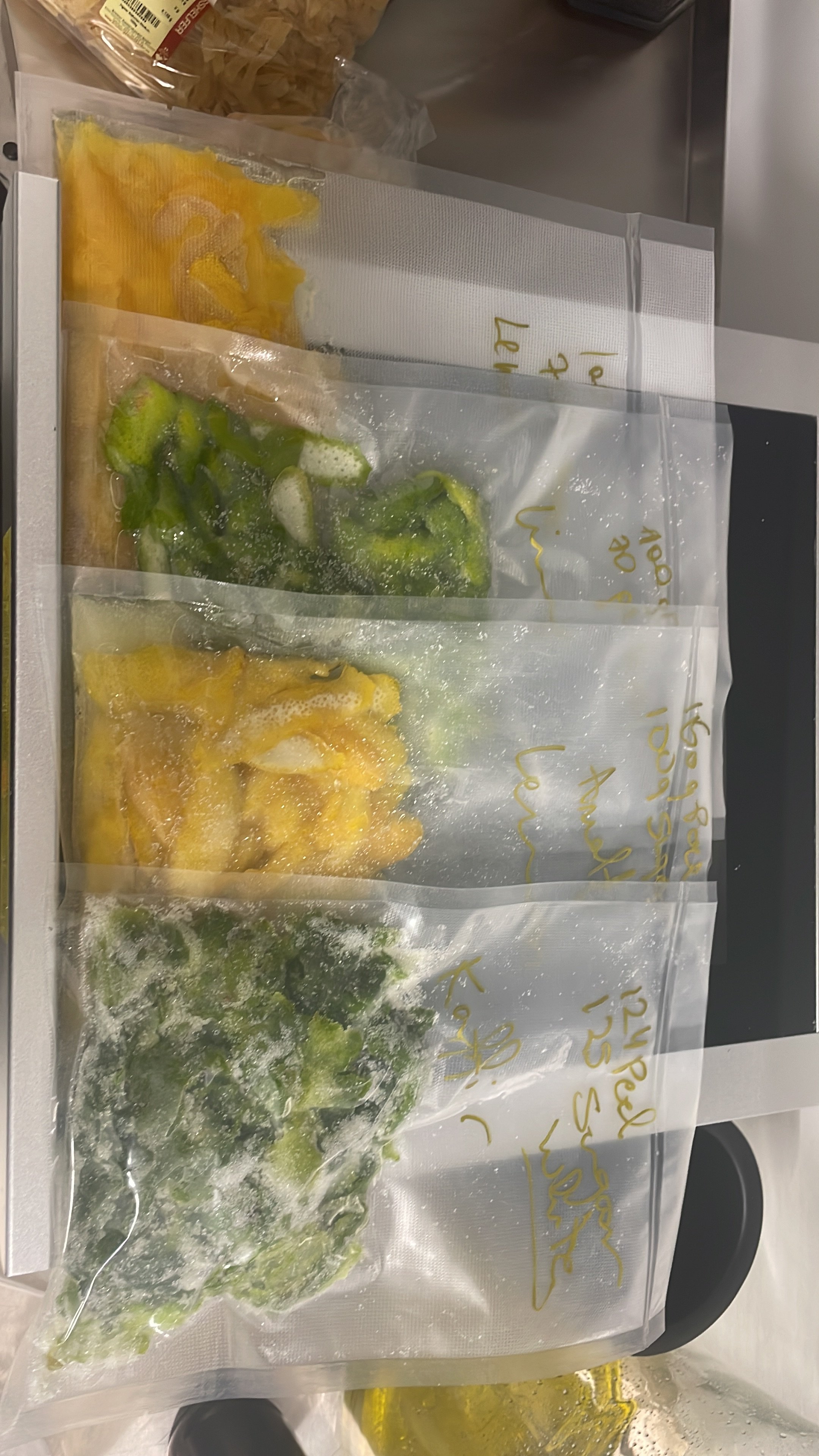 three vacuum-sealed bags containing chopped bell peppers in yellow, green, and mixed colors, resting on a white surface.