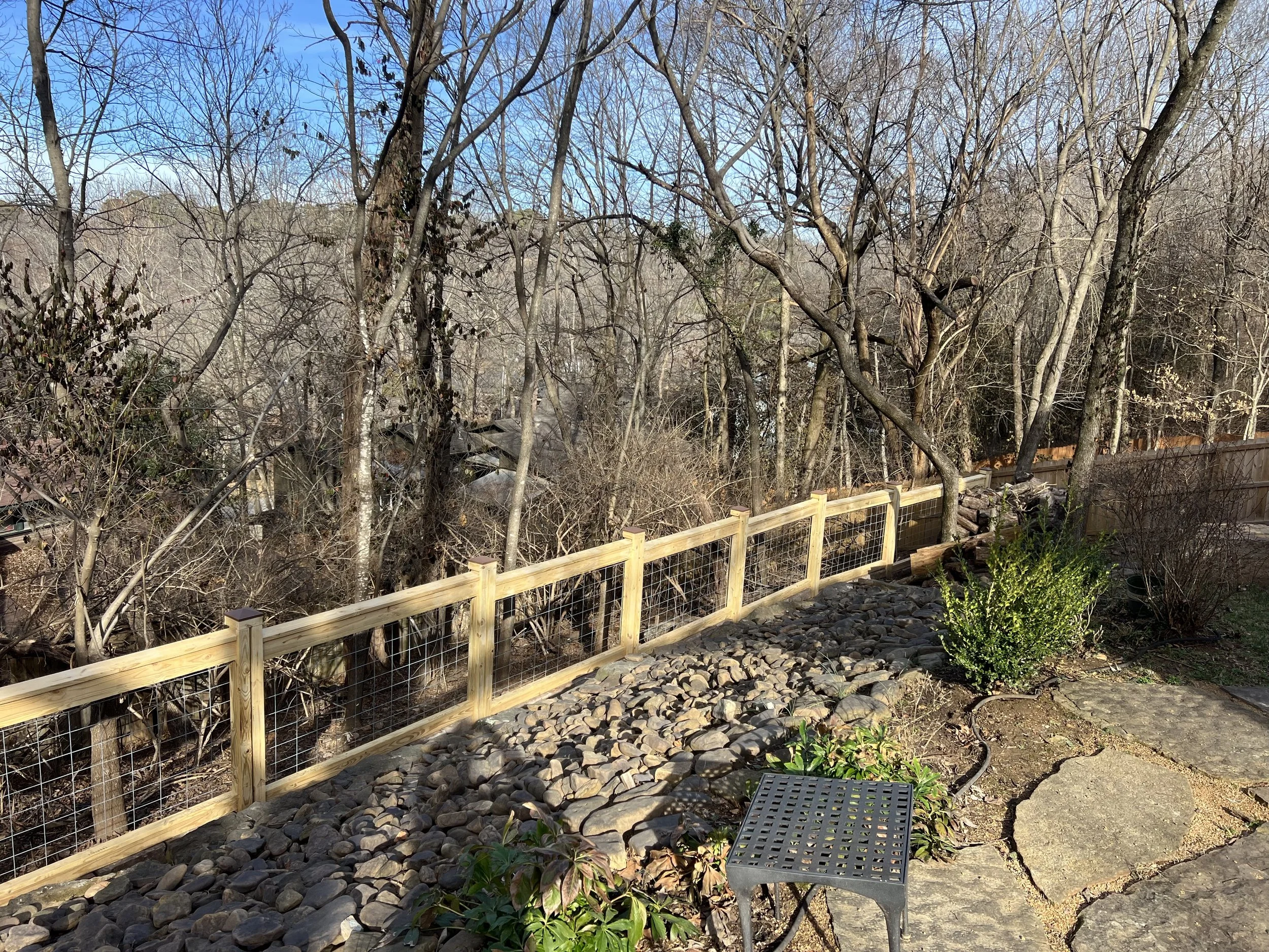 Custom pressure-treated pine and cattle-panel fence along a wooded Mount Sequoyah slope in Fayetteville