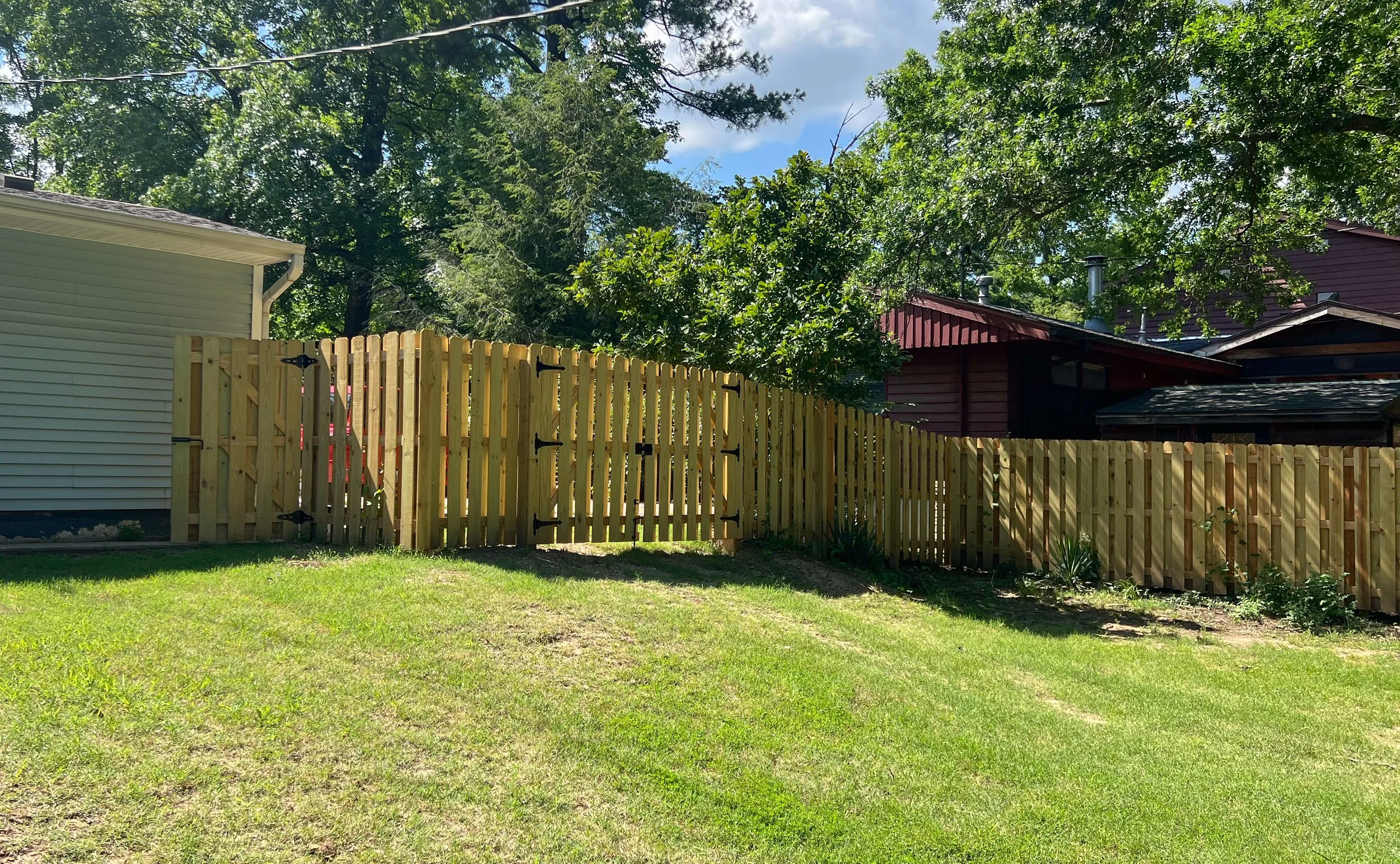 Wide view of shadowbox wood privacy fence and gate along backyard - Fayetteville, AR