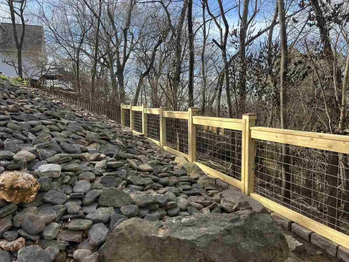 Custom pressure-treated pine and six-gauge wire fence following a rocky Mount Sequoyah slope in Fayetteville, Arkansas.