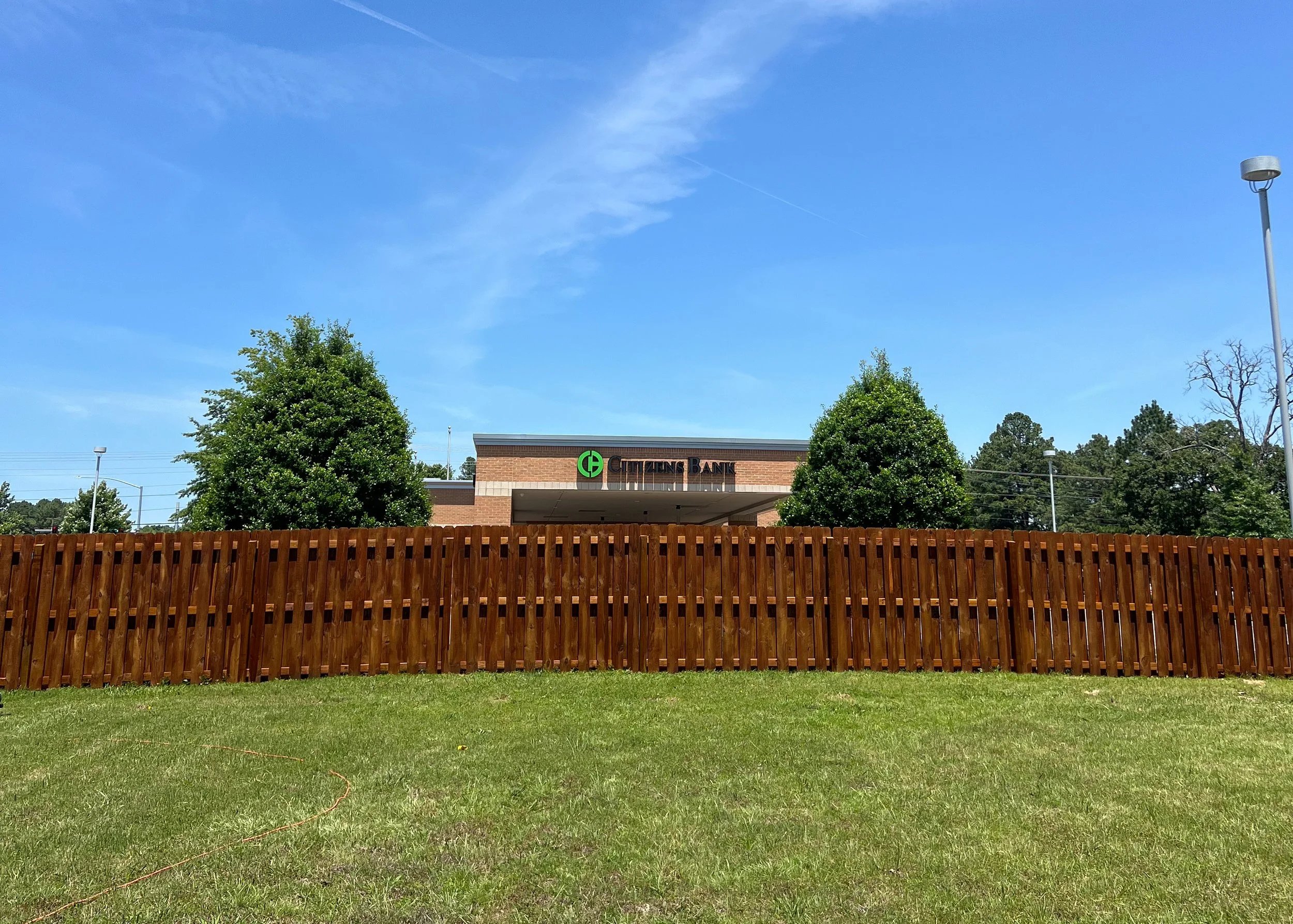 Stained shadowbox wood privacy fence with alternating pickets — Fayetteville, AR