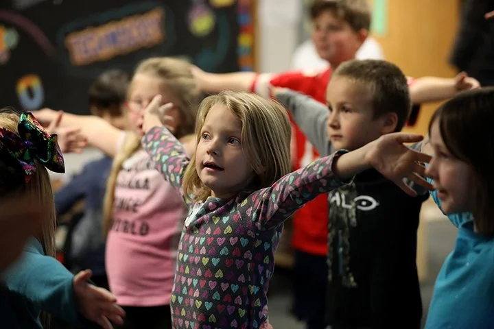 A young girl stretches her arms out in dance