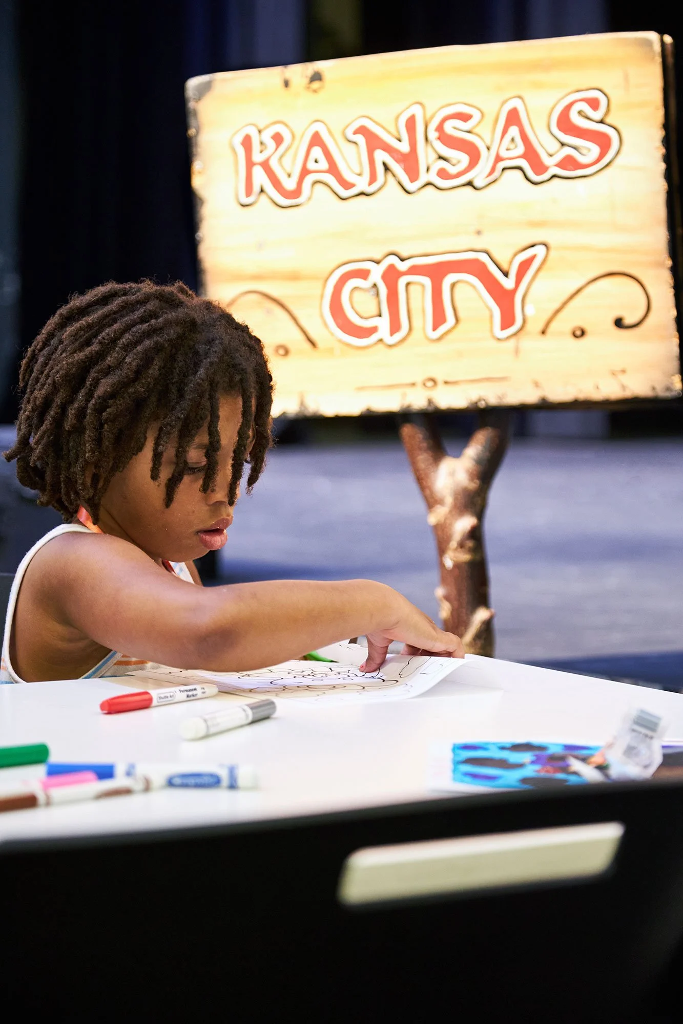 Boy coloring at KCYA with "Kansas City" sign in background