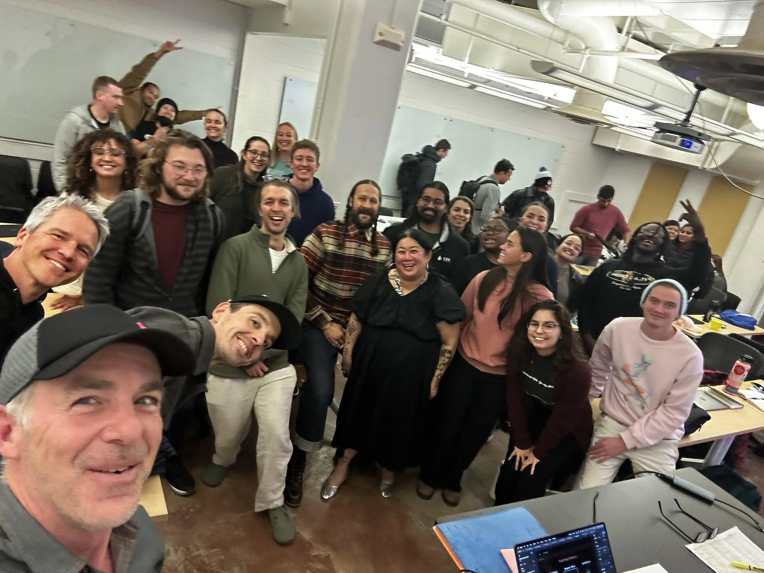 Group of diverse people smiling and making peace signs in a classroom or learning space.