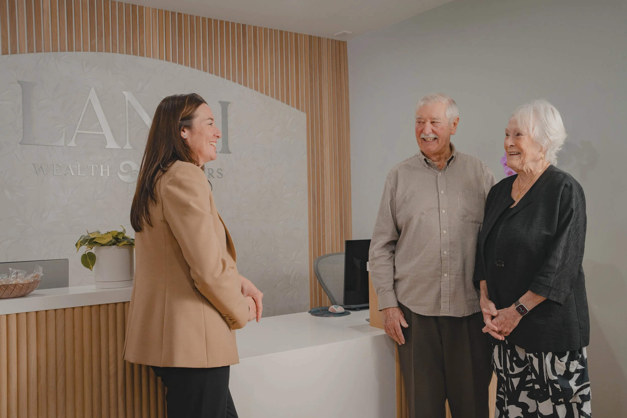 Christine smiling at an older couple in the lobby of Lanai Wealth Advisors.