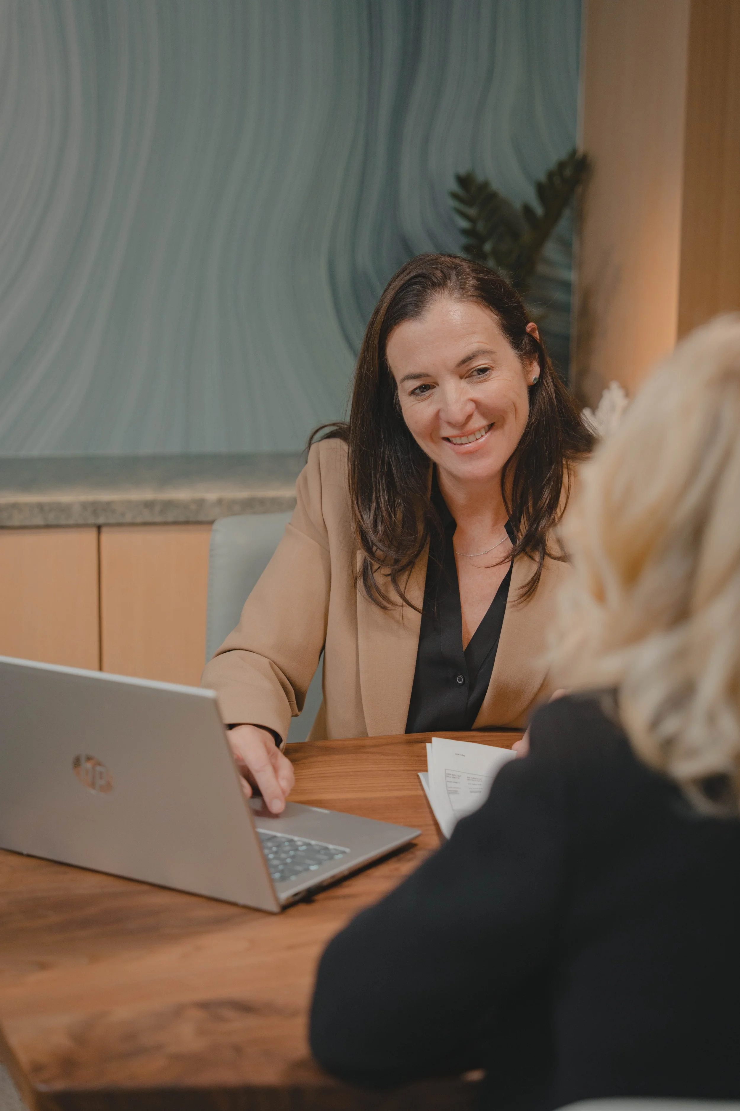 Christine, Founder & President, talking to a woman with her laptop about financial solutions.