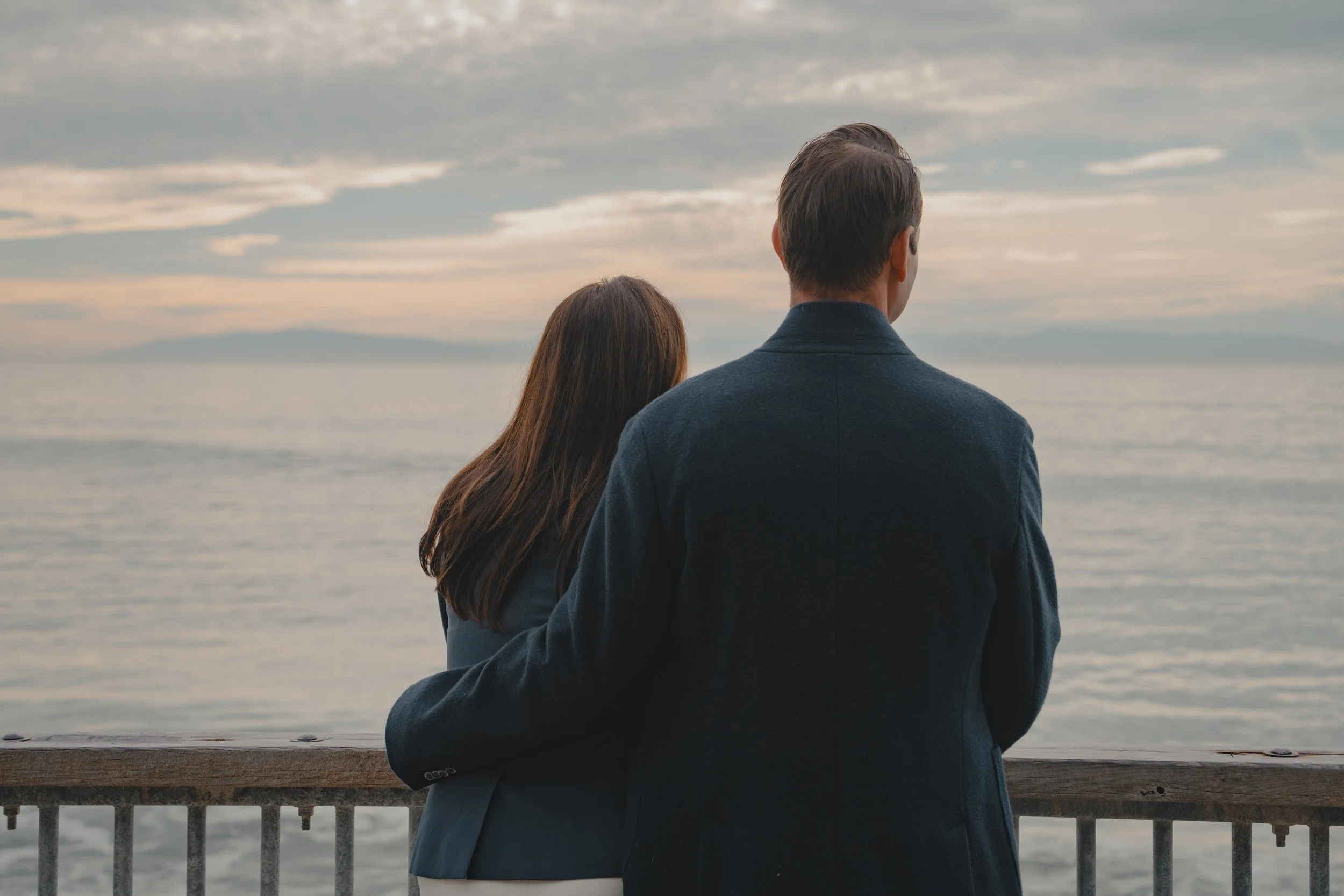 A couple at Capitola Village overlooking the ocean by the guard rail.