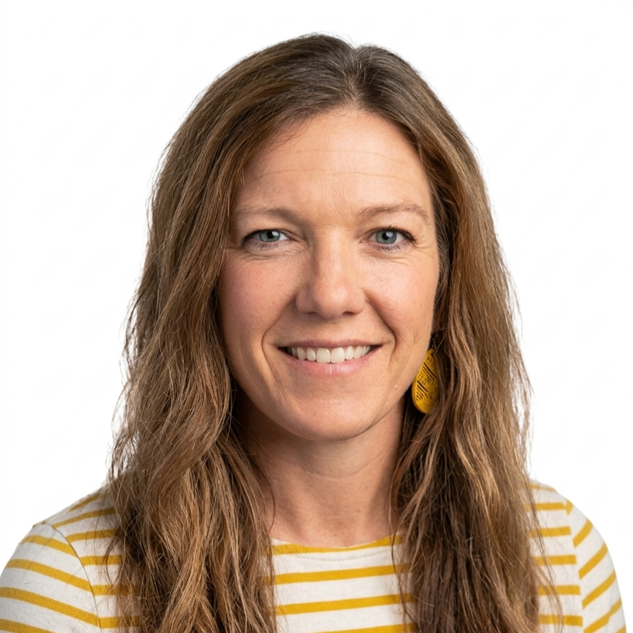 Close-up portrait of a woman with long, wavy brown hair, wearing a yellow and white striped shirt and a yellow earring, smiling against a plain white background.