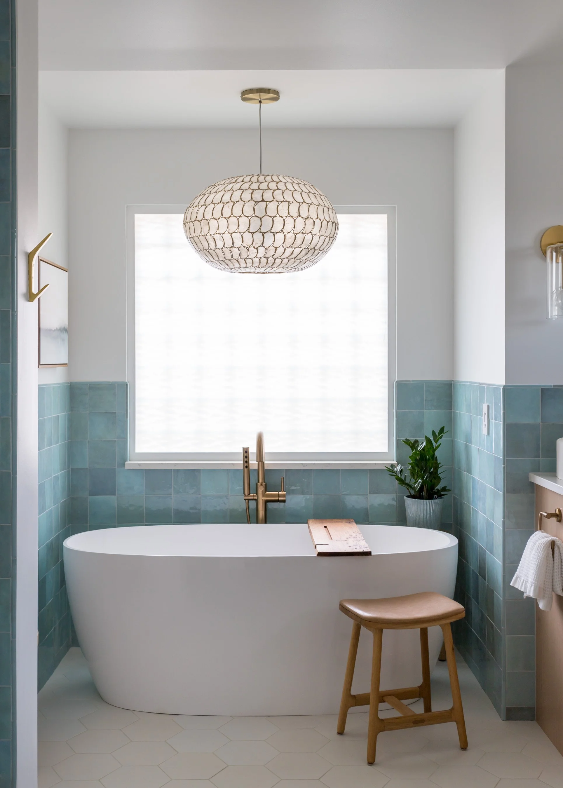 The showstopper: a deep soaking tub framed by soft tilework and crowned with a glam, airy chandelier. Morning routines? Never the same.